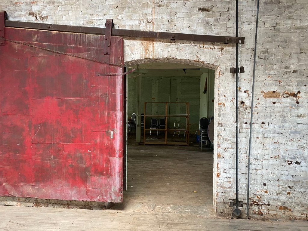 Open red fire door and whitewashed brick wall